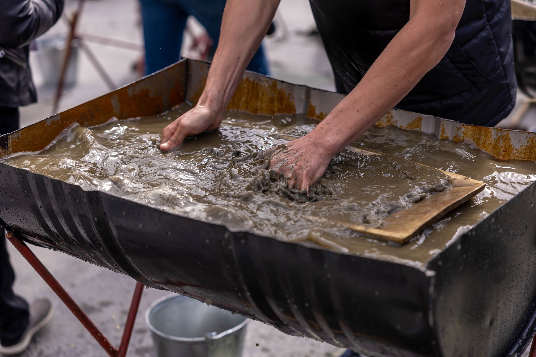 Workers mixing a wet cementitious construction material by hand