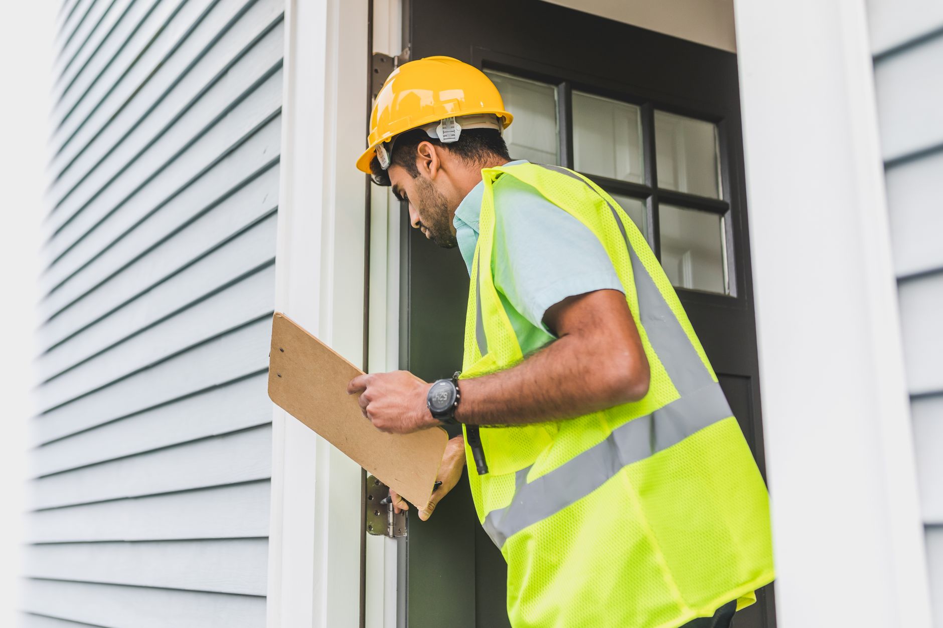 Building inspector in safety equipment checking a property with a clipboard